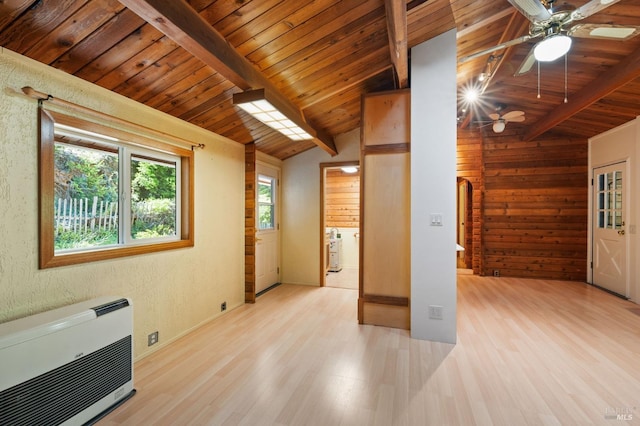 unfurnished living room featuring plenty of natural light, a wood stove, high vaulted ceiling, and light hardwood / wood-style flooring