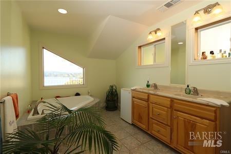 bathroom featuring tile patterned floors, plenty of natural light, a bathtub, and vanity