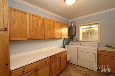 washroom with stone finish flooring, ornamental molding, water heater, cabinet space, and separate washer and dryer