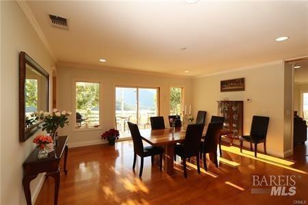 dining area featuring visible vents, crown molding, baseboards, and wood finished floors