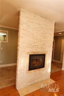 interior details with wood finished floors, baseboards, and a large fireplace