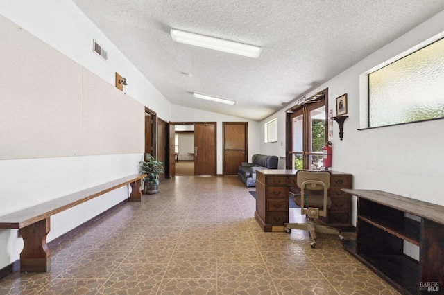 office area featuring a textured ceiling, dark tile floors, and vaulted ceiling