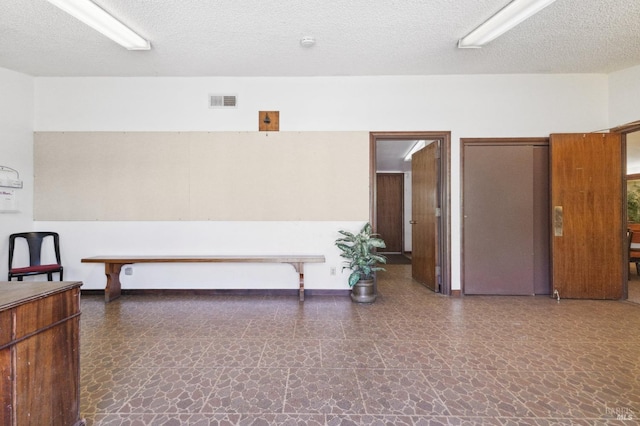 interior space with a textured ceiling and dark tile floors