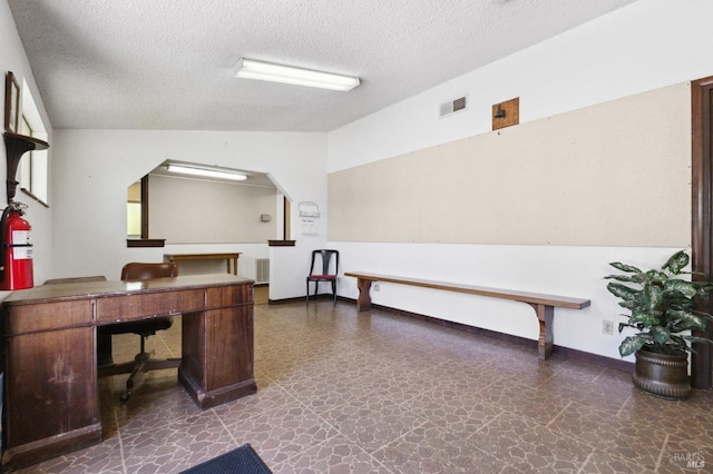 office space with a textured ceiling, radiator, and dark tile floors