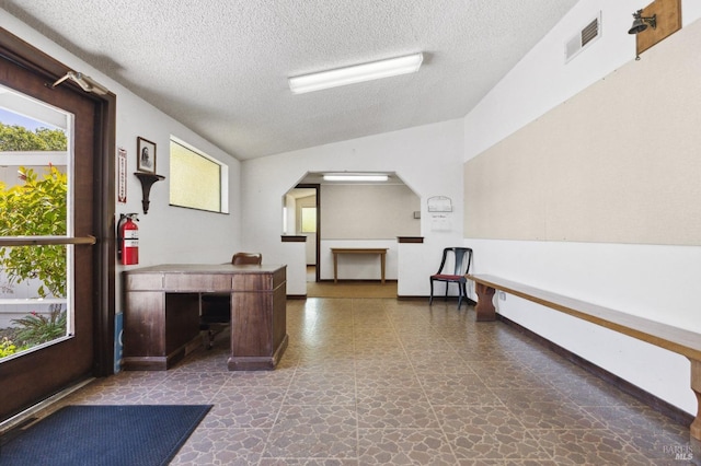 interior space featuring vaulted ceiling, a textured ceiling, and dark tile floors