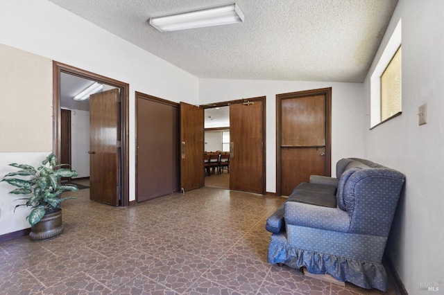 living area with plenty of natural light, a textured ceiling, tile flooring, and vaulted ceiling