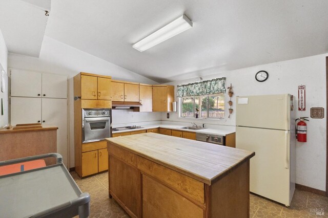 kitchen with vaulted ceiling, a kitchen island, stainless steel appliances, sink, and light tile floors