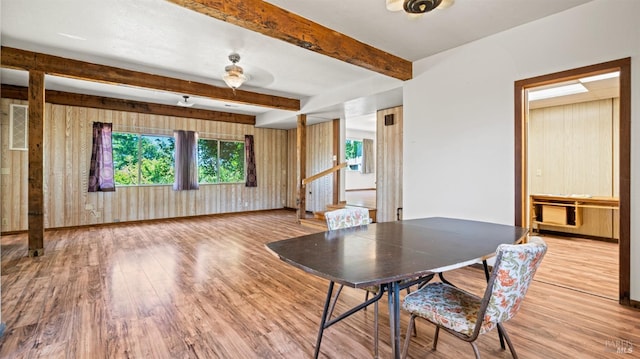 unfurnished dining area with beam ceiling, stairway, baseboards, and wood finished floors