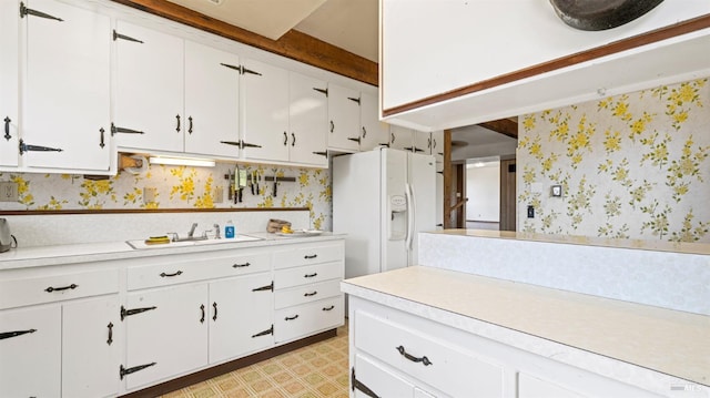 kitchen featuring wallpapered walls, white cabinets, light countertops, light floors, and white fridge with ice dispenser