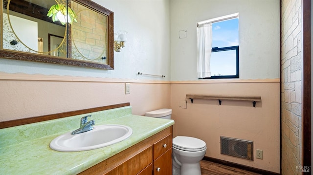 bathroom featuring toilet, wood finished floors, vanity, and visible vents