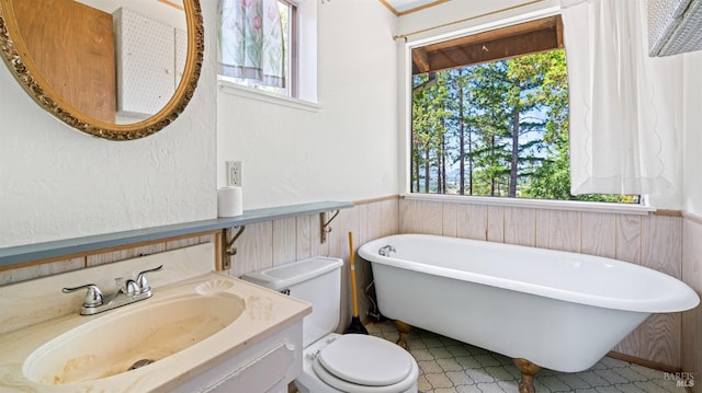 bathroom with toilet, a freestanding bath, a sink, and wainscoting