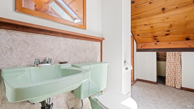 bathroom featuring toilet, vaulted ceiling, and a sink