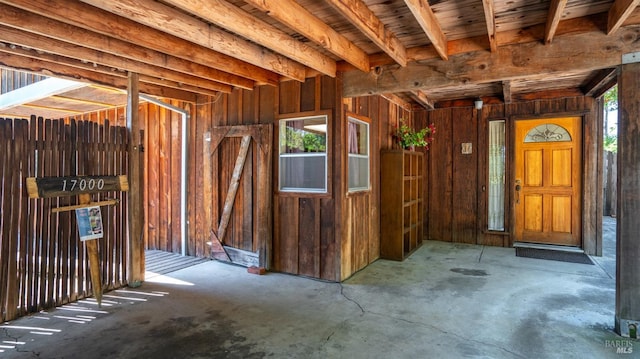 misc room featuring wood walls and unfinished concrete floors