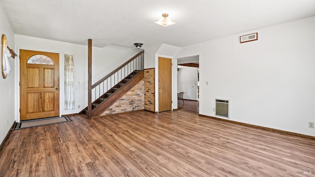 entrance foyer with heating unit, stairs, and wood finished floors