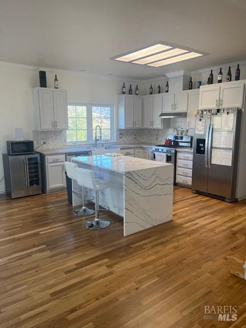 kitchen with stainless steel appliances, white cabinetry, and wood finished floors