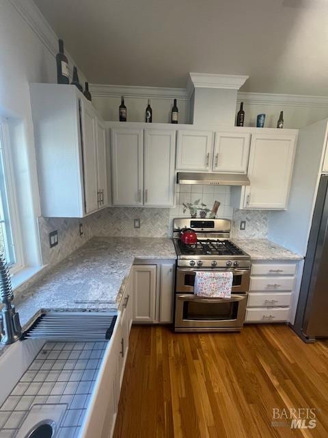 kitchen with dark wood finished floors, freestanding refrigerator, crown molding, under cabinet range hood, and double oven range