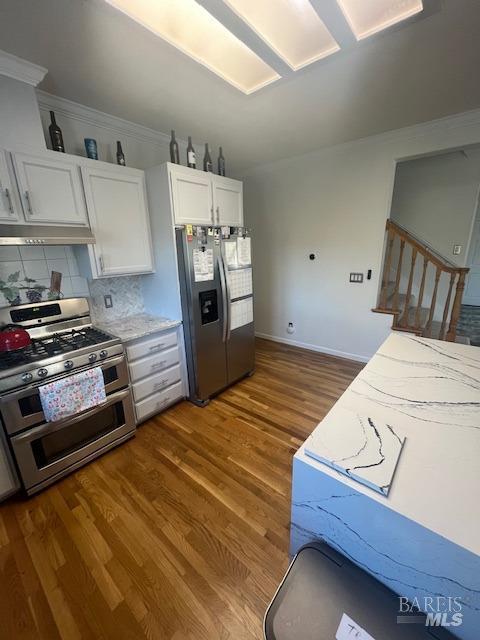 kitchen featuring stainless steel appliances, dark wood-style flooring, white cabinetry, and decorative backsplash