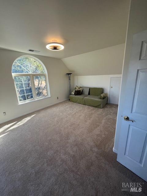 unfurnished living room featuring vaulted ceiling, carpet floors, visible vents, and baseboards