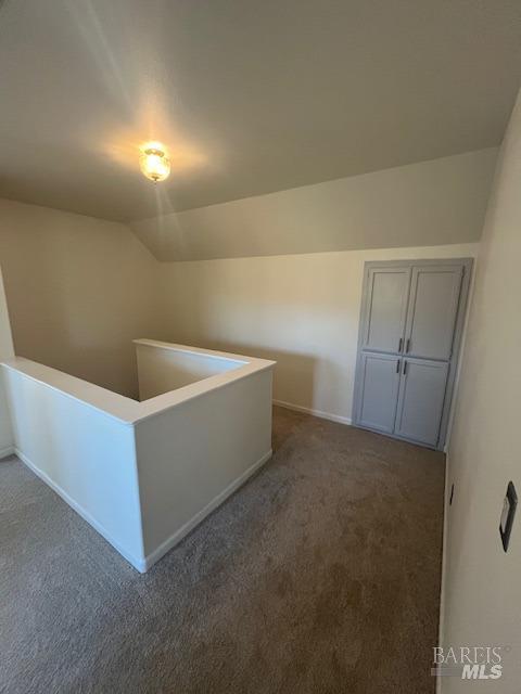 additional living space with carpet flooring, vaulted ceiling, and baseboards