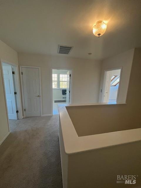 corridor featuring carpet, visible vents, and baseboards