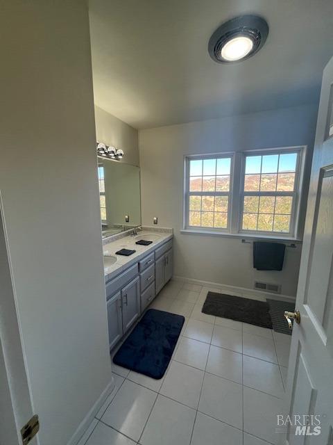 bathroom with double vanity, baseboards, visible vents, tile patterned floors, and a sink