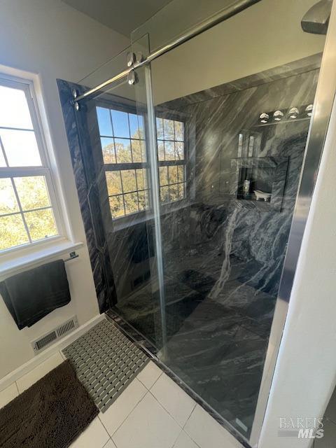 bathroom with visible vents, a marble finish shower, and tile patterned floors