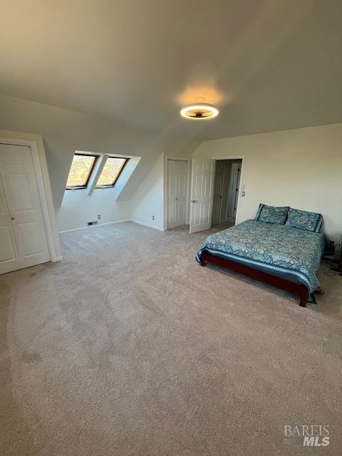 bedroom with light carpet and vaulted ceiling