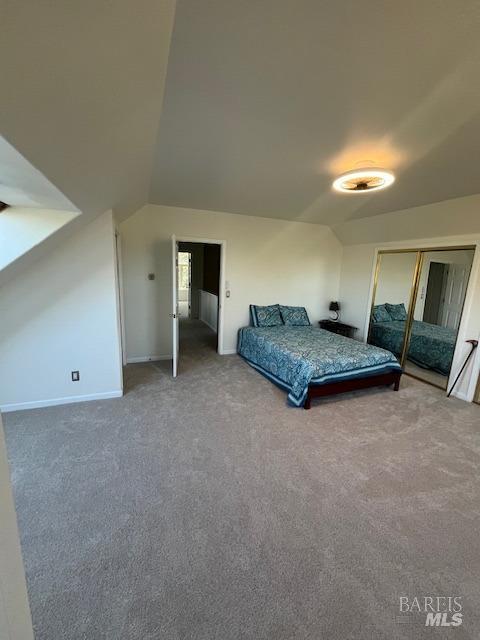 unfurnished bedroom with lofted ceiling, carpet, baseboards, and a closet