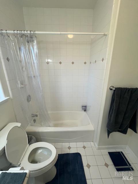 bathroom featuring toilet and shower / bathtub combination with curtain