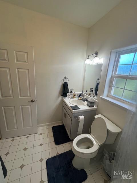 bathroom with toilet, tile patterned flooring, baseboards, and vanity