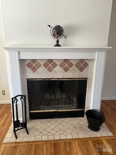 details with a brick fireplace, baseboards, and wood finished floors