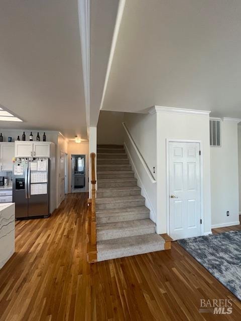 staircase featuring wood finished floors and visible vents