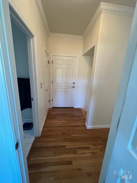 hall featuring baseboards, dark wood finished floors, and crown molding