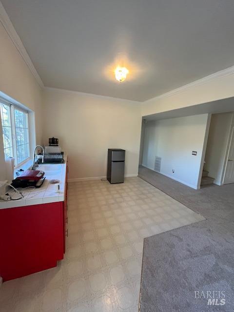 unfurnished office featuring light floors, baseboards, ornamental molding, and a sink