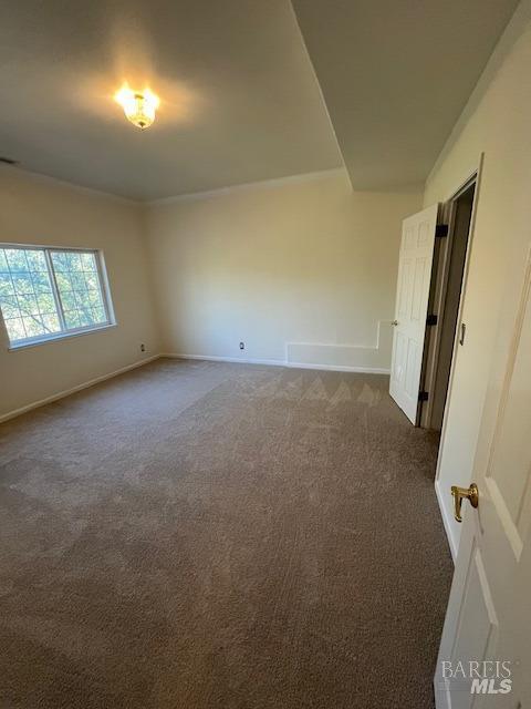 unfurnished room with dark colored carpet and baseboards