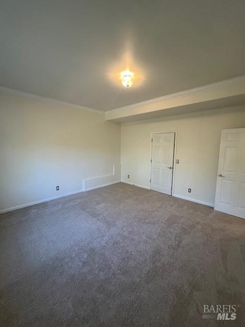 carpeted empty room featuring baseboards and ornamental molding