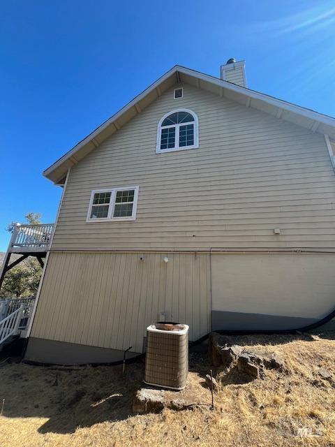 view of property exterior with central AC and a chimney