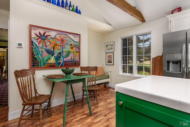 dining area with lofted ceiling with beams and hardwood / wood-style flooring