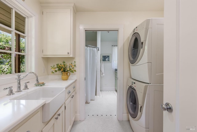 laundry room with cabinets, light tile patterned floors, sink, and stacked washer and clothes dryer