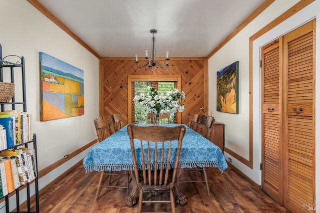 dining space with a notable chandelier, wood walls, crown molding, and dark wood-type flooring