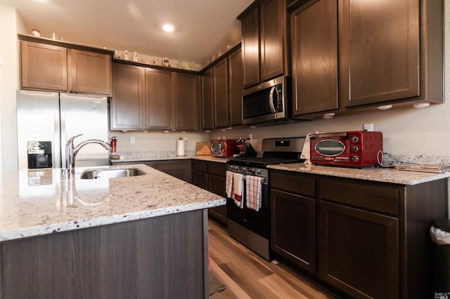 kitchen featuring stainless steel appliances, sink, light stone countertops, and light hardwood / wood-style floors