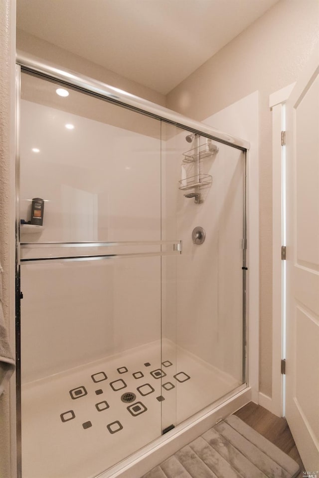 bathroom with a shower with shower door and wood-type flooring