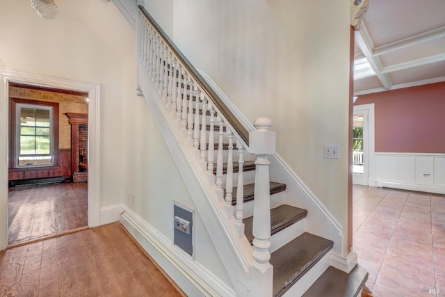 stairway with wood-type flooring, coffered ceiling, beam ceiling, and baseboard heating