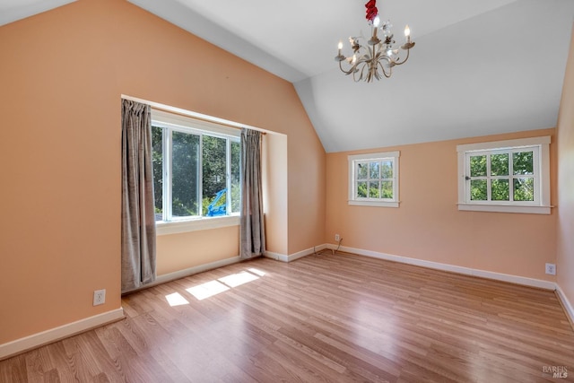 unfurnished room featuring vaulted ceiling, plenty of natural light, a chandelier, and light hardwood / wood-style flooring