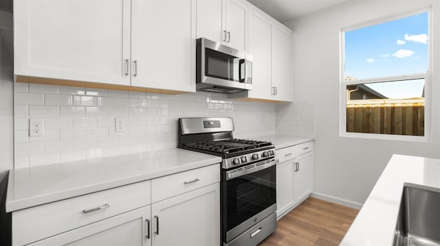 kitchen featuring tasteful backsplash, appliances with stainless steel finishes, white cabinets, and light hardwood / wood-style floors