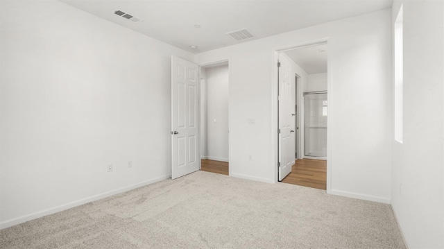 unfurnished bedroom featuring ensuite bath and light carpet