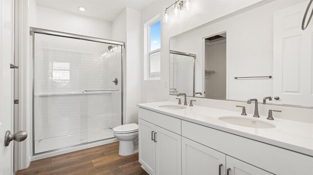 bathroom with hardwood / wood-style flooring, vanity, toilet, and an enclosed shower