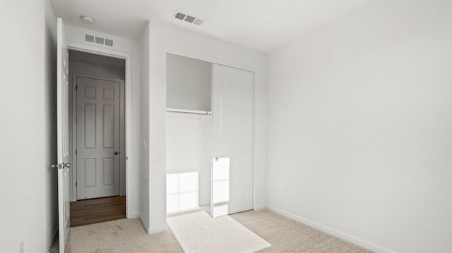 unfurnished bedroom featuring light colored carpet and a closet