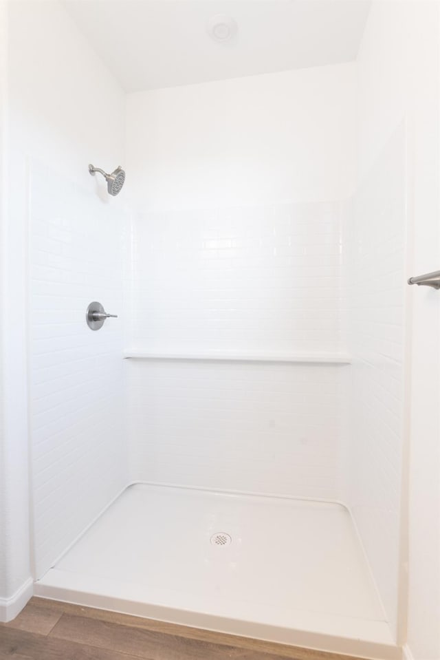 bathroom with a tile shower and hardwood / wood-style flooring