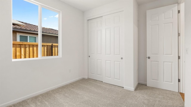 unfurnished bedroom featuring light carpet and a closet